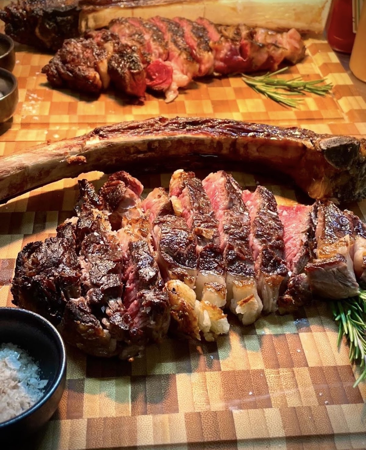 Tomahawk affettato su tagliere con rosmarino e sale